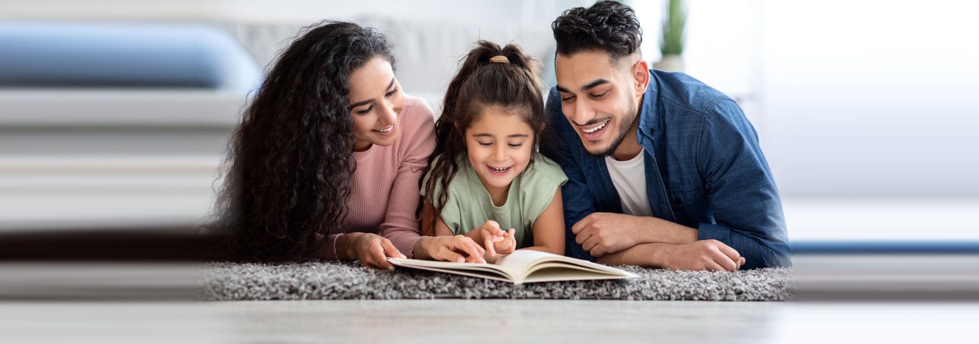 Portraif Of Happy Arabic Family Of Three Reading Book Together At Home